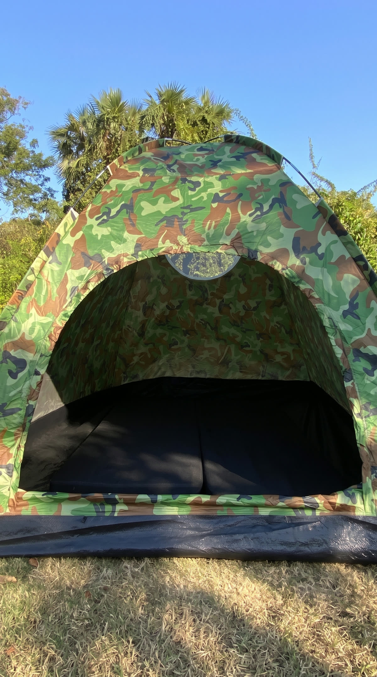 Open camouflage dome tent with black mattresses inside